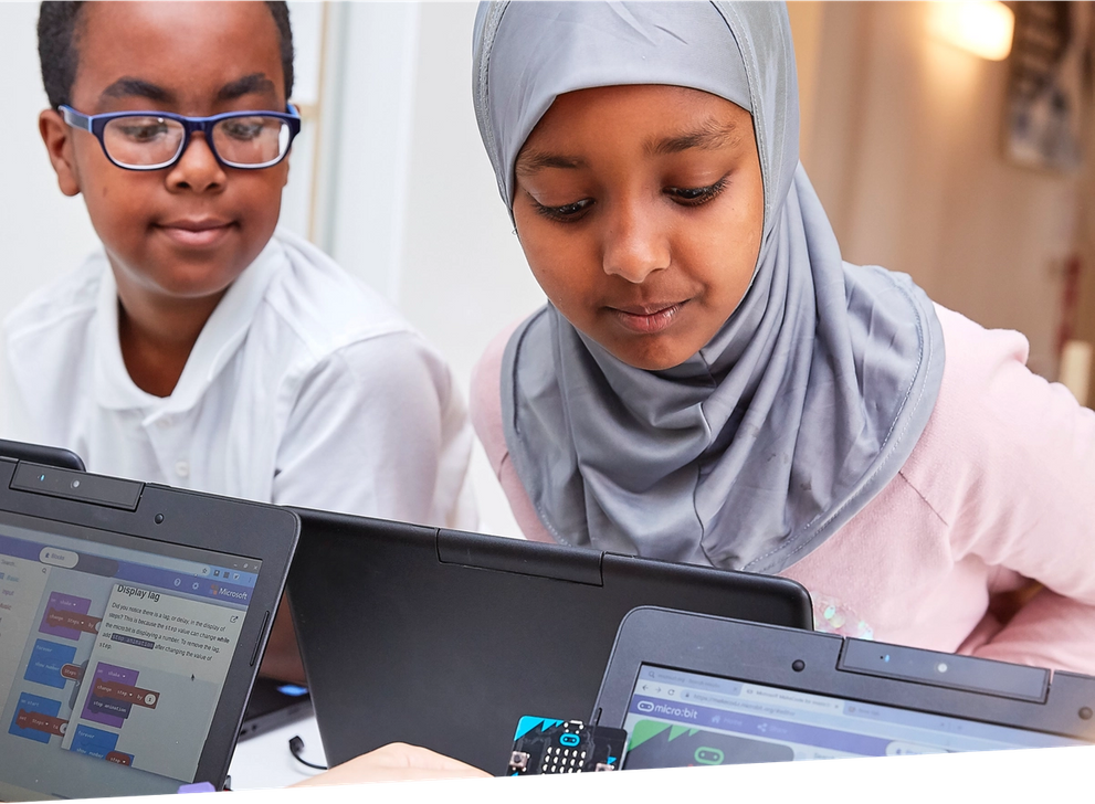 Nens programant micro:bits a classe utilitzant l'editor MakeCode